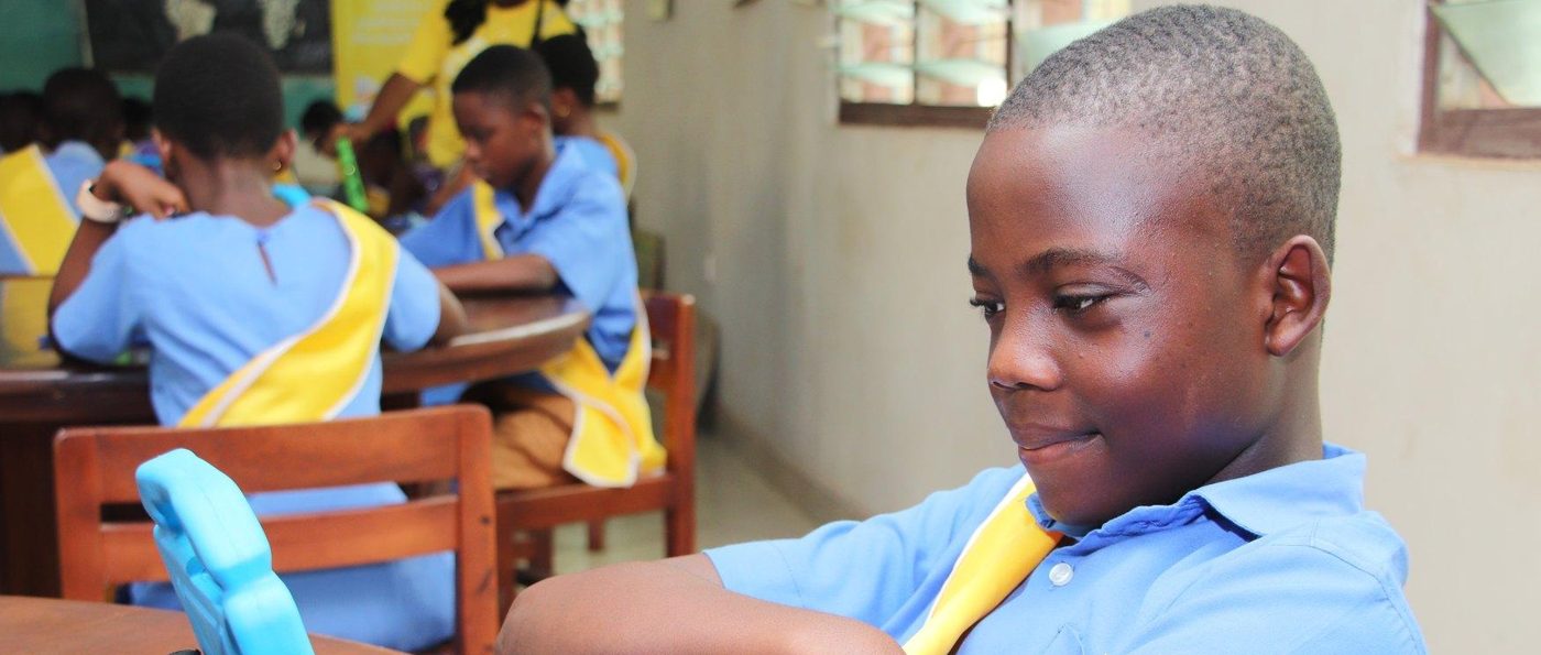 A smiling learner reading on a tablet during a library session